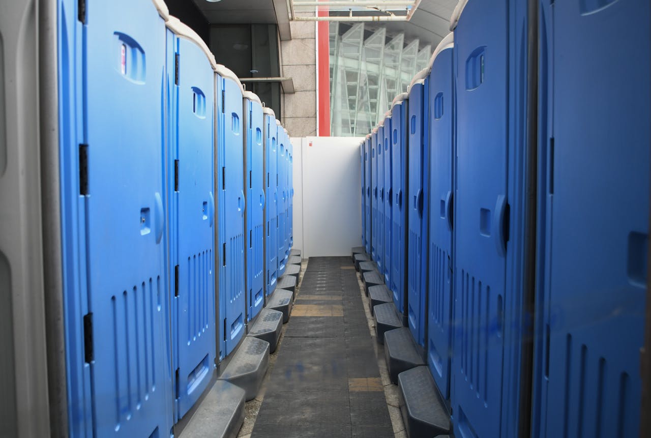 Services A series of blue portable toilets aligned at an outdoor construction site.